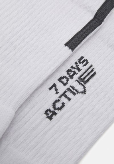 White ribbed fabric with black embroidered text that reads "7 DAYS ACTIVE." Design features a textured surface and a contrasting stripe.
