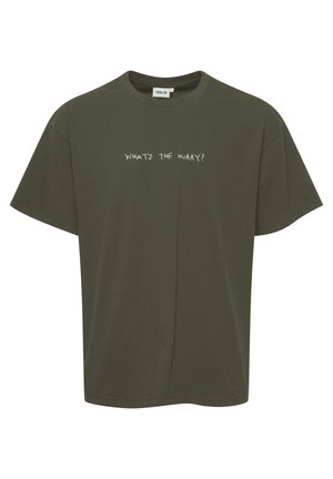 Olijfgroene katoenen T-shirt met een losse pasvorm, korte mouwen en de tekst "WAT IS DE DRINGENDHEID?" in een contrasterende witte lettertype op de voorkant.