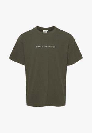 Olijfgroene katoenen T-shirt met een losse pasvorm, korte mouwen en de tekst "WAT IS DE DRINGENDHEID?" in een contrasterende witte lettertype op de voorkant.