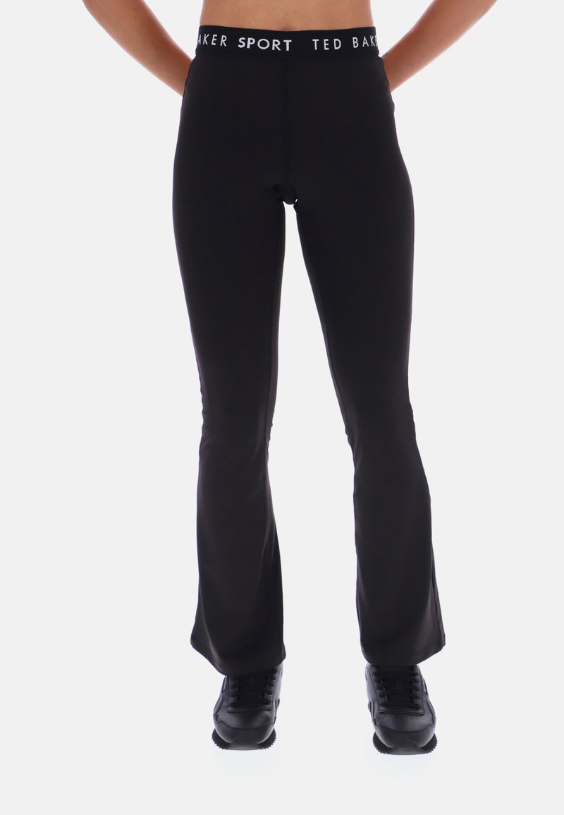 Čierne športové legíny s rozšíreným strihom a vysokým pásom, na ktorých sa nachádza biely pás s logom "Ted Baker SPORT", vyrobené z pružného a hladkého materiálu.