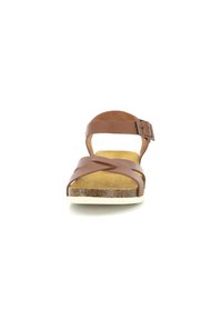 Sandalo in pelle marrone con cinturini incrociati e fibbia regolabile alla caviglia, dotato di un soletta simile al sughero e suola in gomma bianca.