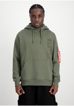 Sudadera verde oliva con bolsillo frontal, capucha con cordón y detalle de logo en relieve. Presenta una etiqueta roja en la manga y puños acanalados.