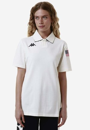 Polo shirt bianco in cotone, con colletto nero e logo ricamato sul lato sinistro del petto, e bandiera americana sulla manica.
