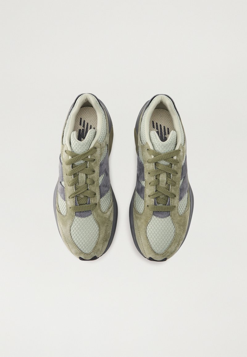 Baskets pour hommes avec une tige en mesh et suède en vert olive et gris, dotées de lacets ronds et d'un col rembourré. Semelle texturée pour une meilleure adhérence.