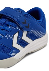 Blauer Sportschuh mit Netzobermaterial, weißen Akzenten und einem Klettverschluss. Verfügt über eine strukturierte Sohle und ein gepunktetes Verlaufsdesign.