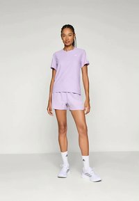 Fialový športový outfit pozostávajúci z trička s krátkym rukávom a zodpovedajúcich šortiek. Vyrobené z ľahkého materiálu, s jemným logom.