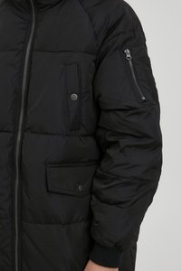 Black puffer jacket made from a smooth, shiny material. Features a front zipper, patch pocket with a snap, and a zippered sleeve pocket.
