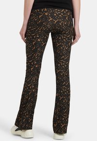 Zvlněné kalhoty s designem v černo-hnědém zvířecím potisku. Vyrobené z texturovaného materiálu, s elastickým pasem a přiléhavým střihem.