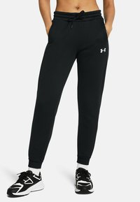 Zwarte joggingbroek met een elastische tailleband, trekkoord, zijzakken en een klein wit logo op het linkerbeen, gemaakt van zachte stof.