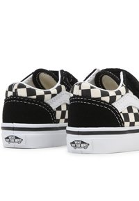 Baskets à enfiler en noir et blanc à motifs de damier, en suède et toile, avec une semelle blanche et le logo "Vans Off the Wall".