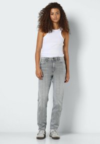Light gray jeans with a straight leg fit, stitched seams, five pockets, and a mid-rise waist, paired with a white sleeveless top.