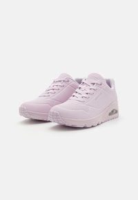 Light pink athletic shoes with a smooth synthetic upper, textured details, and a thick sole featuring a transparent air cushioning element.