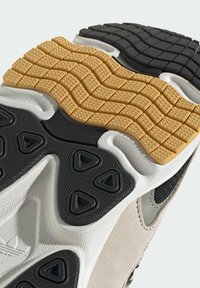 Sneaker sole featuring a multi-textured design with a yellow rubber section, black sections with triangular grips, and white textured accents.