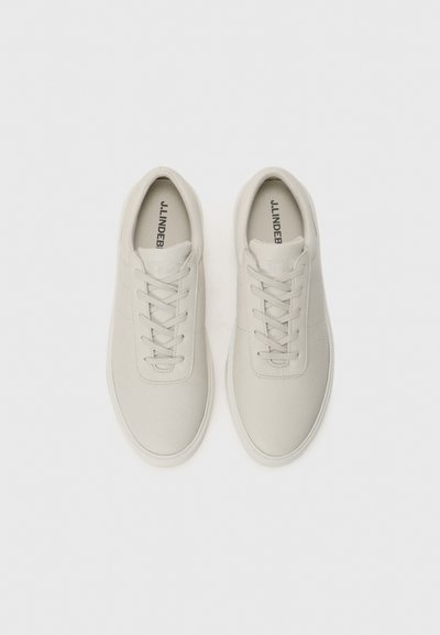 Light gray sneakers with a smooth texture, round toe, flat white laces, and minimalistic design. Branding visible on the insole.