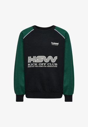 Barn iført sort hue, sort og grøn sweatshirt med teksten "KICK OFF CLUB", sorte bukser og sorte sneakers, stående mod en hvid baggrund.