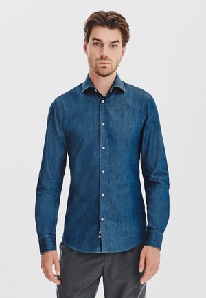 Jeansowa koszula w ciemnoniebieskim kolorze, z długimi rękawami, guzikiem z przodu i rozłożonym kołnierzykiem. Gładka faktura z białymi guzikami. Dopasowany krój.