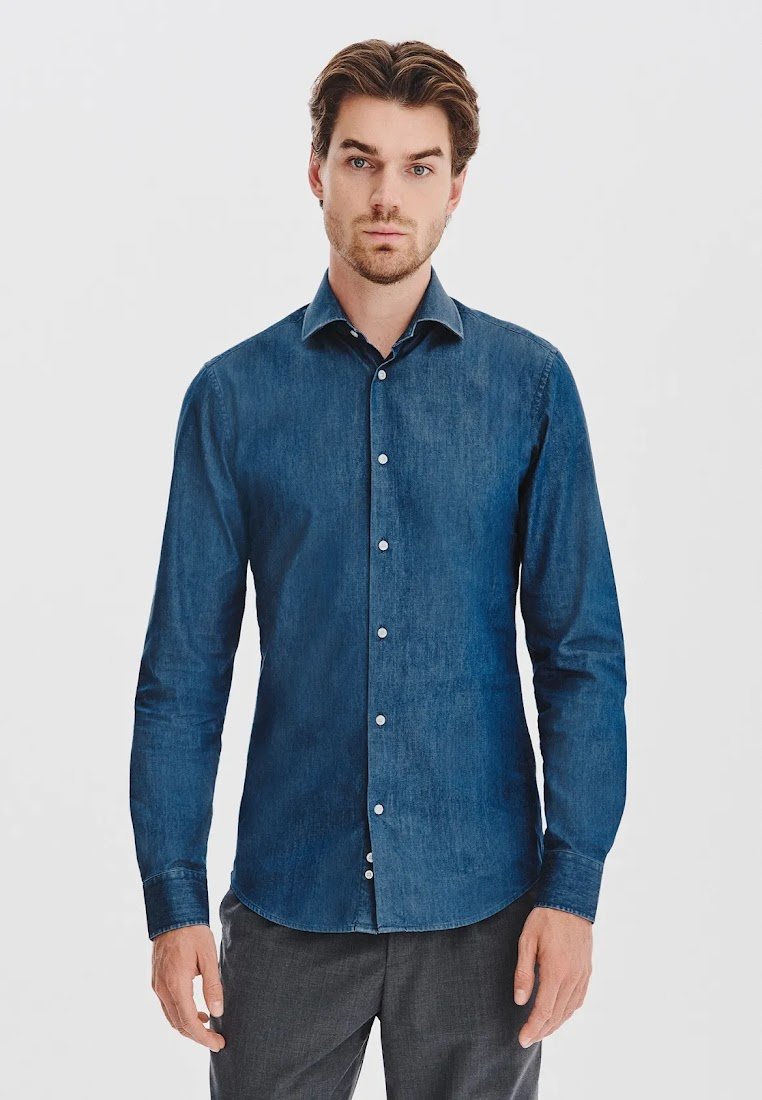 Jeansowa koszula w ciemnoniebieskim kolorze, z długimi rękawami, guzikiem z przodu i rozłożonym kołnierzykiem. Gładka faktura z białymi guzikami. Dopasowany krój.