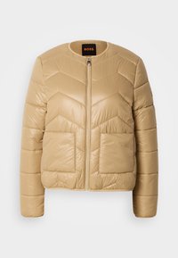 Beige doorgestikte jas met chevronstiksels, twee voorzakken, ronde halslijn en een ritssluiting aan de voorkant, met BOSS-label aan de binnenkant van de kraag.