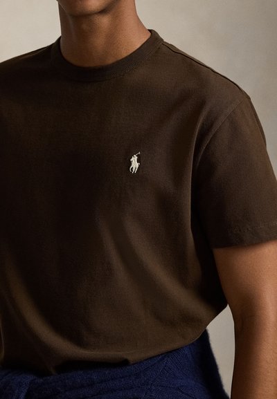 Tricou maro din bumbac, cu guler rotund bordurat și un mic logo brodat pe pieptul stâng. Textură moale, cu mâneci scurte.