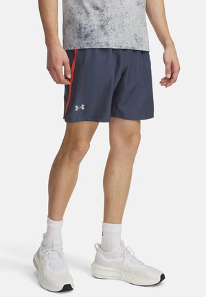 Herre navy atletiske shorts lavet af letvægtsstof, med røde striber på siden og et logo. Båret med hvide sneakers og ankelstrømper.