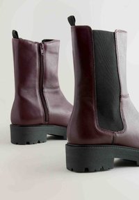 Botine din piele burgundă, cu fermoar lateral și panou elastic, talpă din cauciuc negru texturat și toc mic.