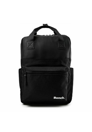 Mochila Black Bench con asas superiores, bolsillo frontal con cremallera, bolsillos laterales y forma rectangular sobre fondo blanco.