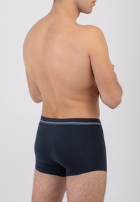 Boxer shorts blu scuro in tessuto morbido, con elastico in vita caratterizzato da una striscia grigia chiara, e una vestibilità aderente che copre i fianchi e le cosce.