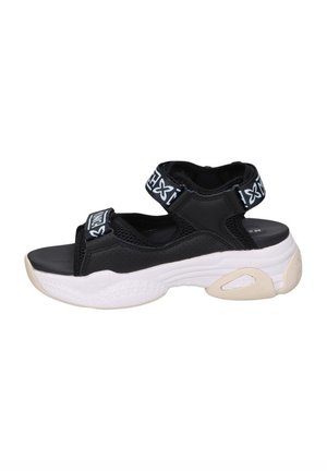 Sanda negra con correas ajustables, diseño de punta abierta y una suela intermedia blanca texturizada con forma redondeada.