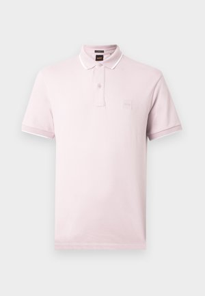 Polo cor-de-rosa clara em algodão, com gola de botões, mangas curtas e um pequeno emblema com o logótipo no peito. Detalhes brancos na gola.