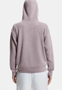 Sudadera con capucha de color lila claro con un corte holgado, que presenta una textura suave, una capucha grande y puños acanalados. Detalle de logo en el dobladillo.