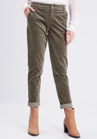 Olijfgroene corduroy broek met een slim fit, omgeslagen broekspijpen en voorzakken. Gecombineerd met tan enkellaarsjes voor contrast.