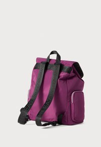 Paarse nylon rugzak met zwarte logo schouderbanden, bovenklep sluiting en een zijvak met rits. Gladde textuur en modern ontwerp.