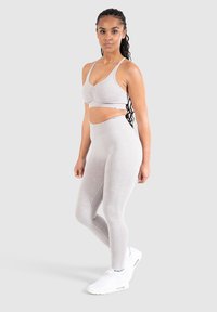 Grå sportbh och högmidjade tights tillverkade av mjukt och stretchigt material. Har en rynkad design på bh:n och en jämn yta överlag.