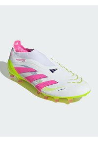 Crampon de football blanc avec une surface texturée, des accents roses et verts, et un design ressemblant à une chaussette. Présente une technologie de toucher hybride.