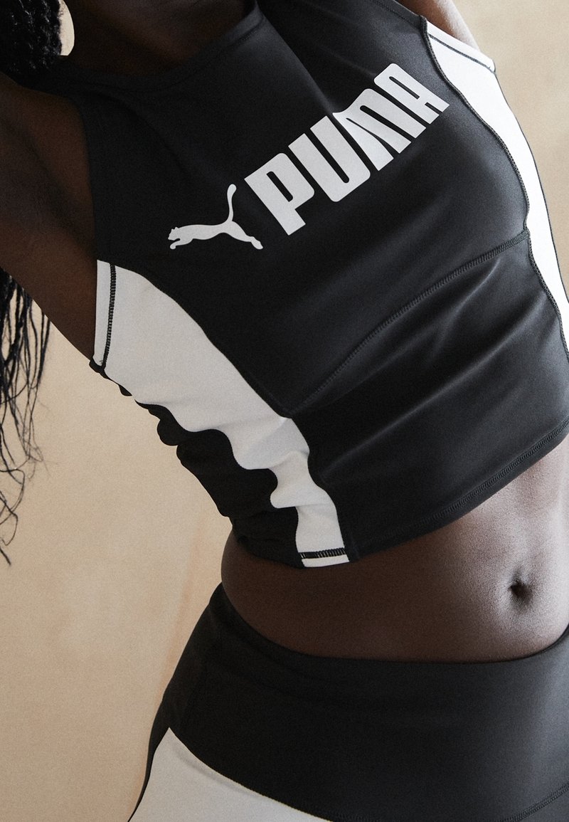 Czarny sportowy top crop z białymi akcentami, z wyraźnym białym logo 'PUMA'. Wykonany z gładkiego, elastycznego materiału o dopasowanym kroju.