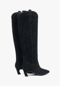 Černé semišové kozačky ke kolenům s špičatou špičkou a robustním podpatkem. Mají jemné švy a zadní poutka pro snadné nazouvání.