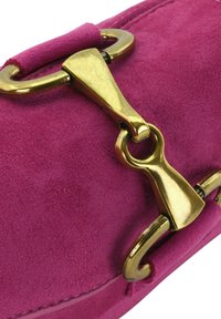 Borsa in suede rosa con hardware dorato e una chiusura distintiva. Tessuto liscio con bordi arrotondati e dettagli di cucitura minimi.