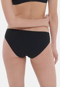 Czarne majtki bikini wykonane z gładkiego materiału, charakteryzujące się klasycznym krojem i bezszwowymi brzegami dla komfortu. Prosty design bez widocznych logo.