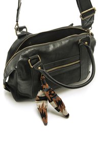 Sac à main en cuir noir avec des zippers dorés, deux poignées et une bandoulière réglable. Inclut un accessoire en tissu à motifs sous forme de pompon.