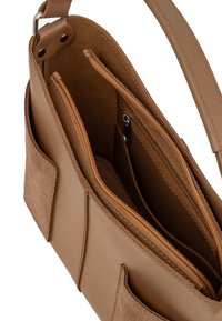 Borsa a mano in pelle color tan con molteplici scomparti; presenta una tasca con zip e accenti in suede. Texture liscia e design minimalista.