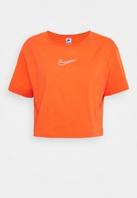 Zkrácené oranžové bavlněné tričko s kulatým výstřihem a krátkými rukávy, s bílým logem Nike na levé hrudi.