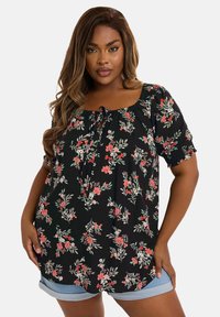 Svart blommig blus med korta elastiska ärmar, fyrkantig halsringning och knytning fram, prydd med rosa och gröna blommönster.
