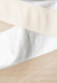 Lagret lærmateriale i beige, krem og sølv med en jevn tekstur, med buede og vinklede former i en myk fargepalett.