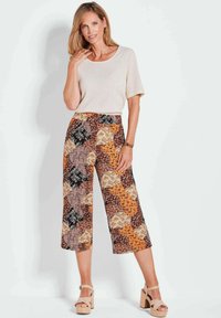 Beige korte mouw top in combinatie met wijde broek met een meerkleurige bloemen- en geometrische print, textuurstof en een relaxte pasvorm.