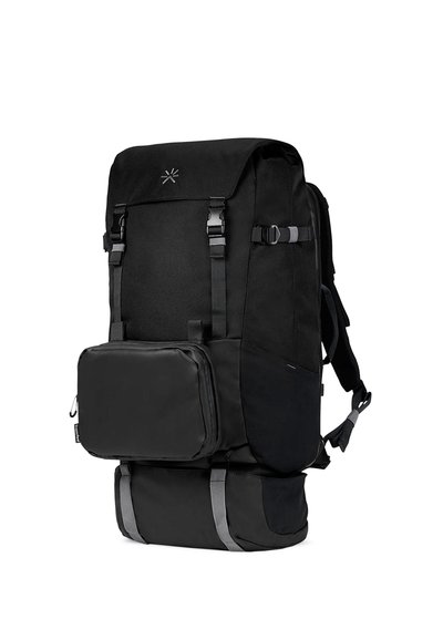 Mochila negra de forma rectangular, cuenta con un amplio compartimento, correas ajustables y un bolsillo frontal desmontable. Tejido texturizado con acentos grises.