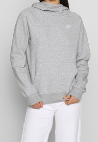 Grå munkjacka med framficka, ribbade ärmar och nederdel. Har en liten vit Nike-logga på bröstet. Mjuk tygkänsla.