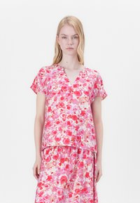 Top a maniche corte e scollo a V in tessuto leggero, con un motivo floreale rosa e dettagli in rosso e lavanda. Vestibilità rilassata.