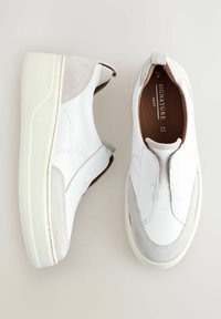 Chaussures blanches en cuir à enfiler avec des accents en suédine grise, bout rond et épaisse semelle blanche, présentant des coutures détaillées et une semelle intérieure à logo.