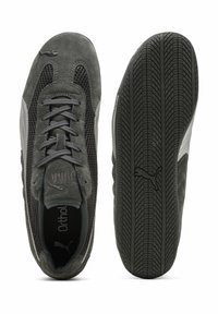 Zapatillas de ante gris con paneles de malla, suelas planas de goma negra y cordones a tono. El lado presenta un acento en blanco y el logotipo de la marca.