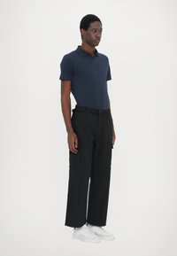 Marinblå polo shirt, svarta cargobyxor med fickor och vita sneaks. Slim fit, korta ärmar och mjuk tygkvalitet.
